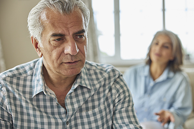 IMAGE: woman and man appear as if arguing. Man in foreground appears perplexed, while woman in background gestures and seems to be asking a question.