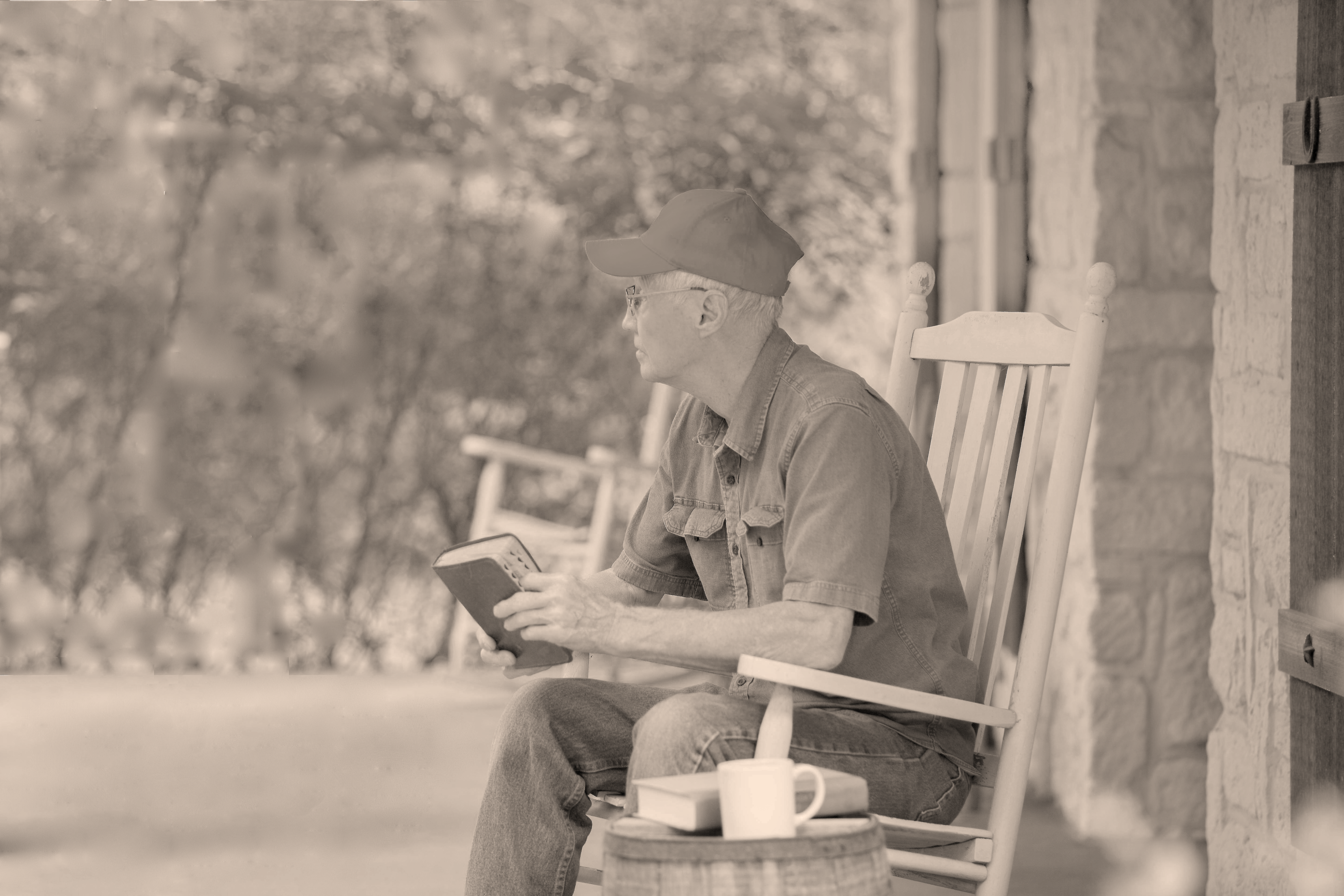 IMAGE: man in rocking chair on porch; appears lost in thought.