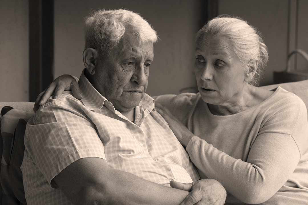 IMAGE: man and woman sitting  side by side, woman appears to be consoling man who looks frustrated