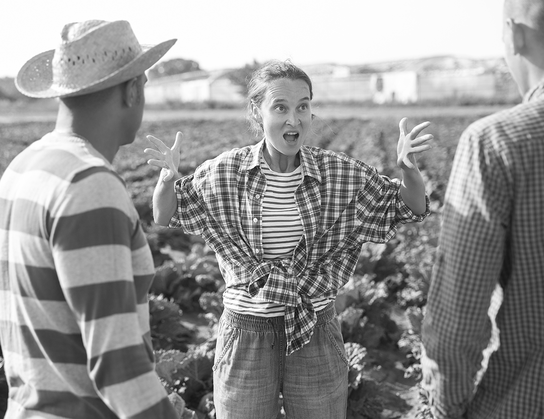 IMAGE: angry woman waving her hands while two men look on in a field of crops